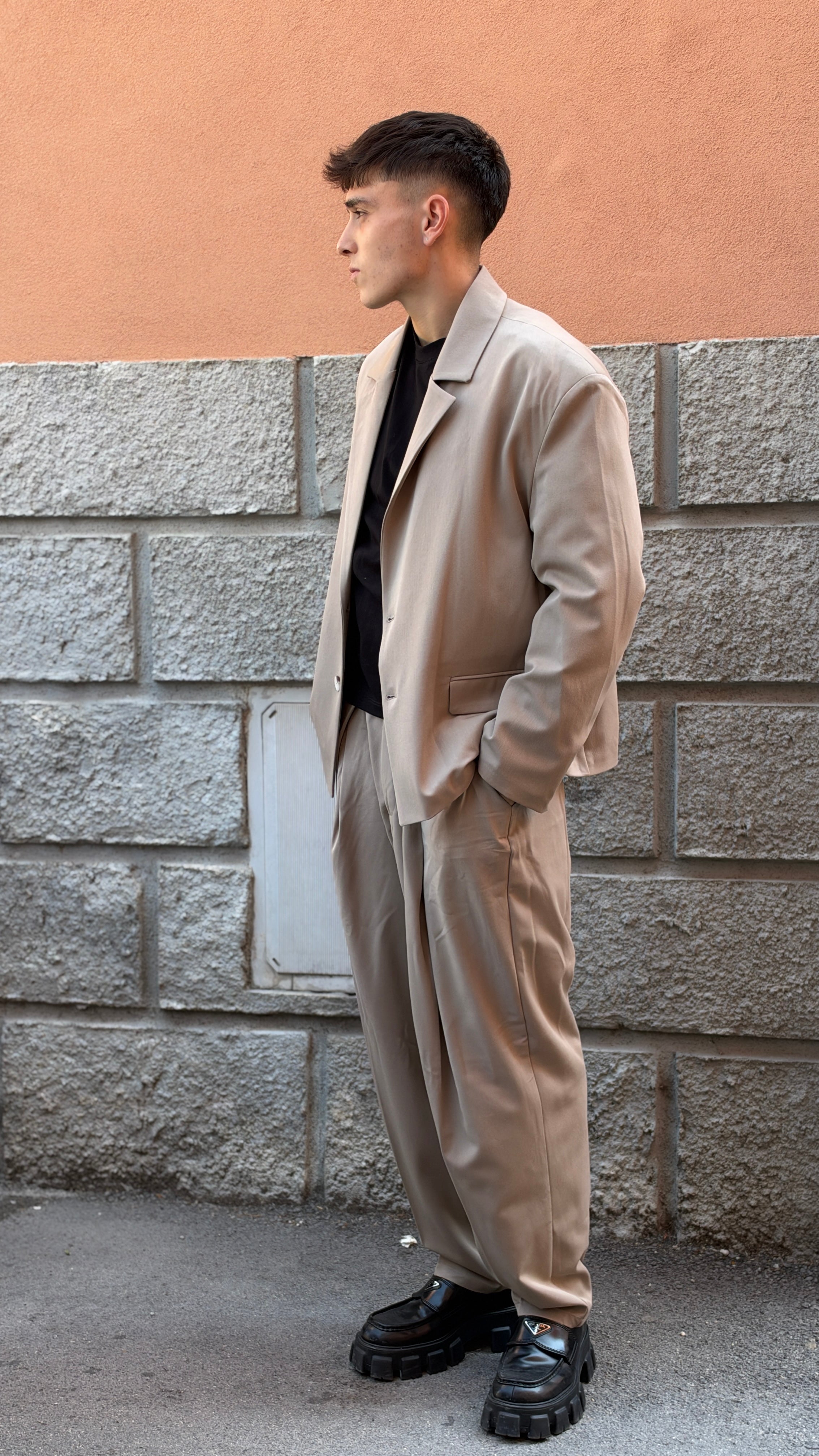 Tailleur beige con giacca crop e pantalone largo.