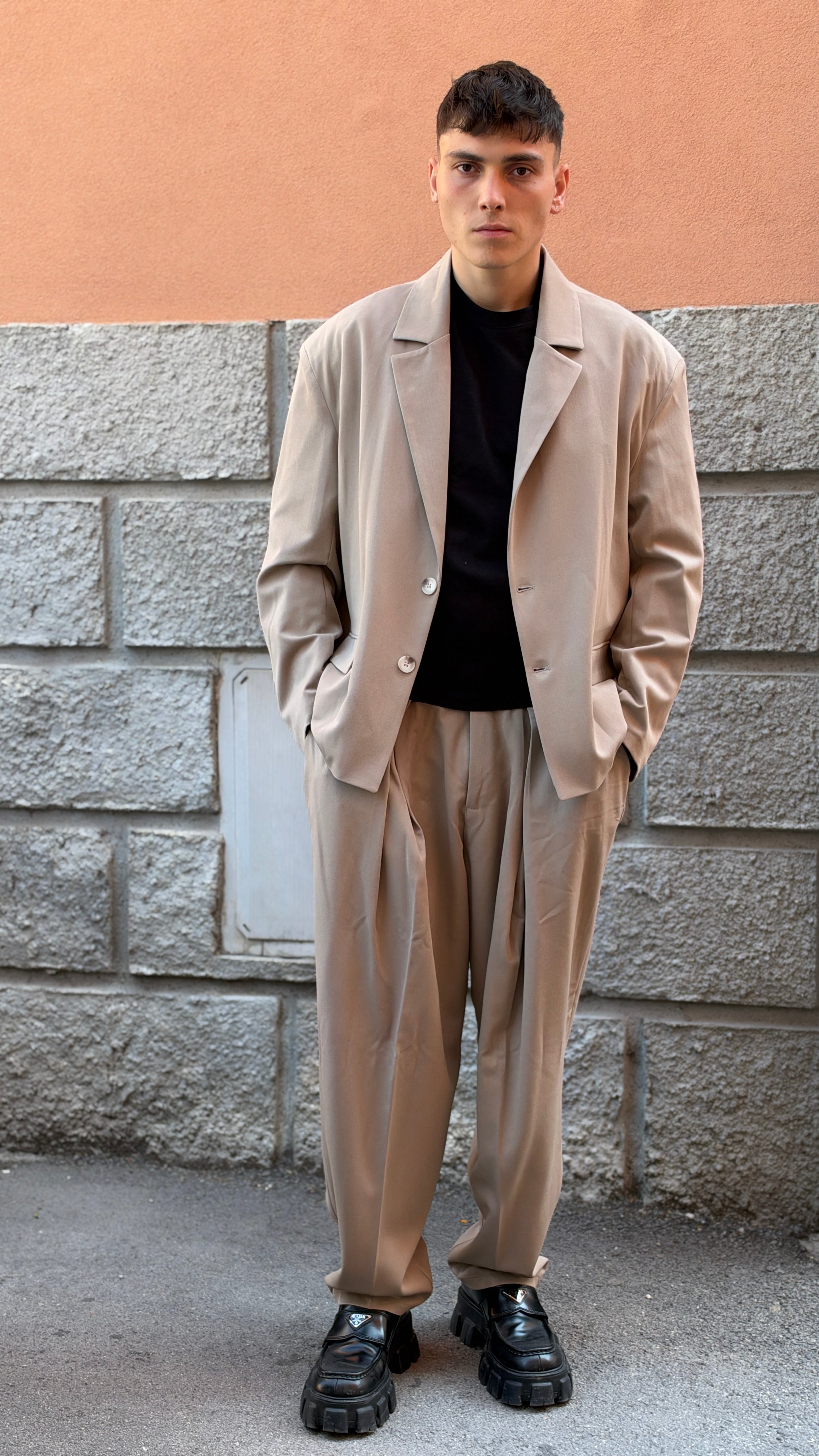 Tailleur beige con giacca crop e pantalone largo.