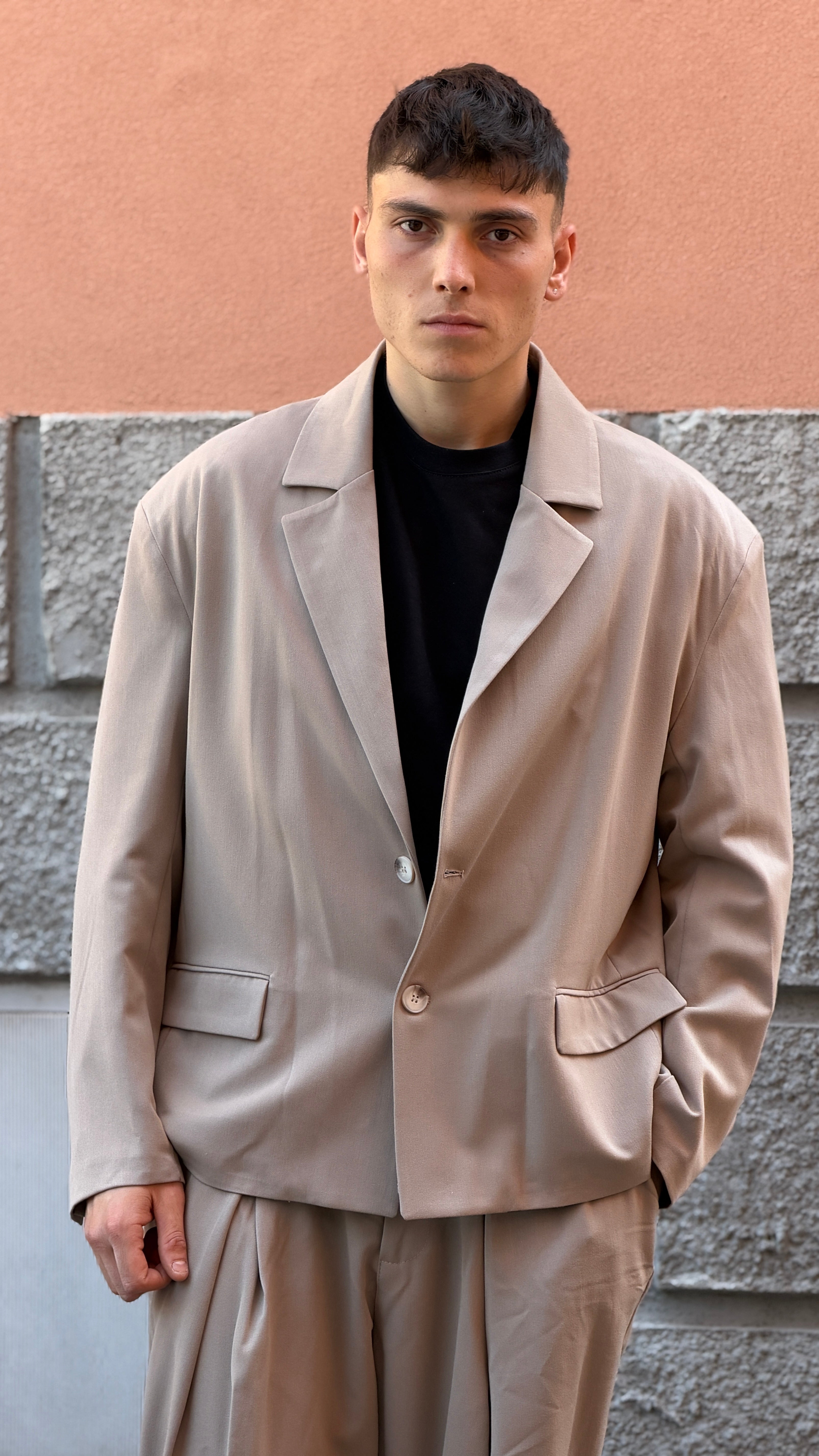 Tailleur beige con giacca crop e pantalone largo.