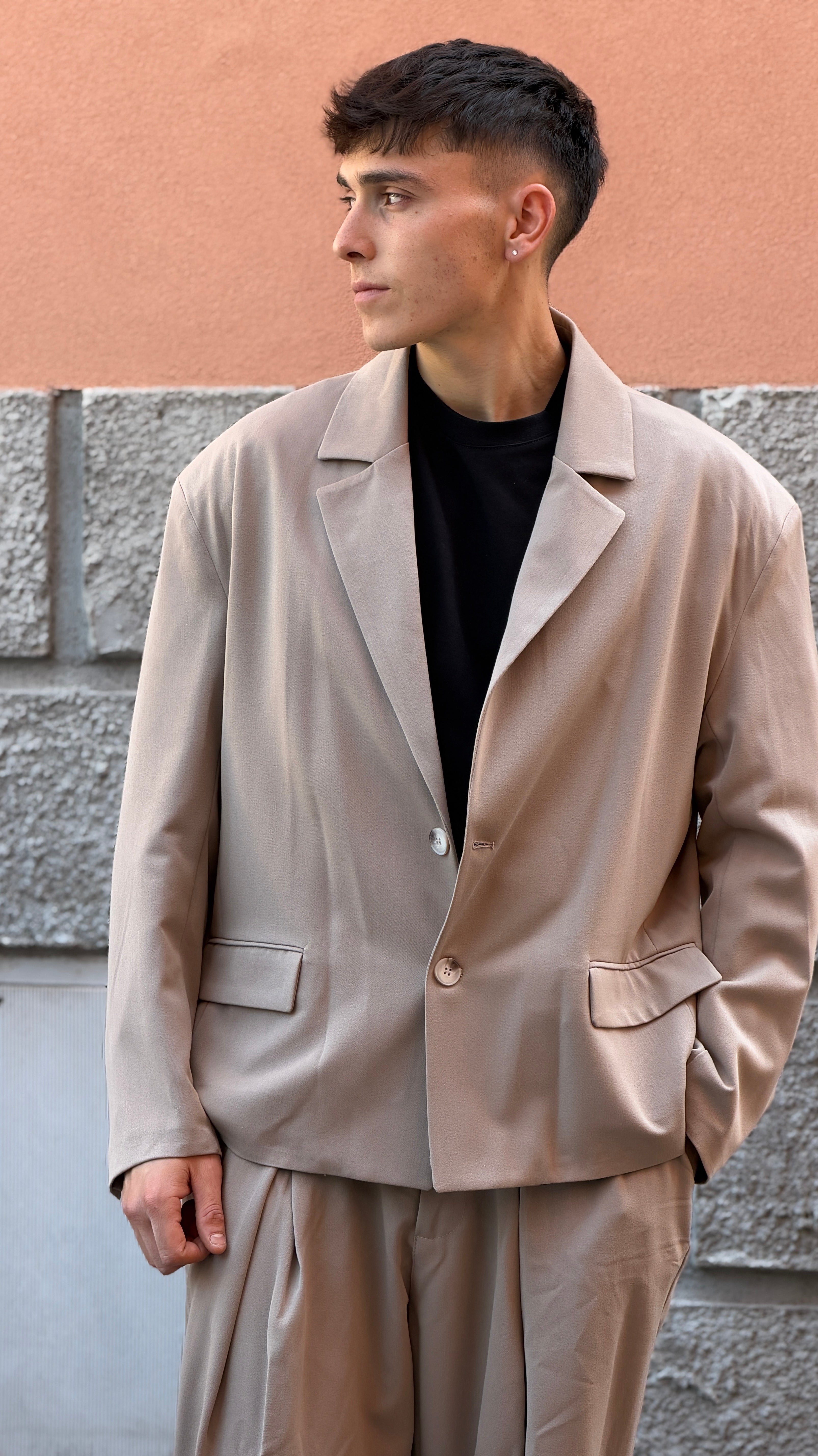 Tailleur beige con giacca crop e pantalone largo.