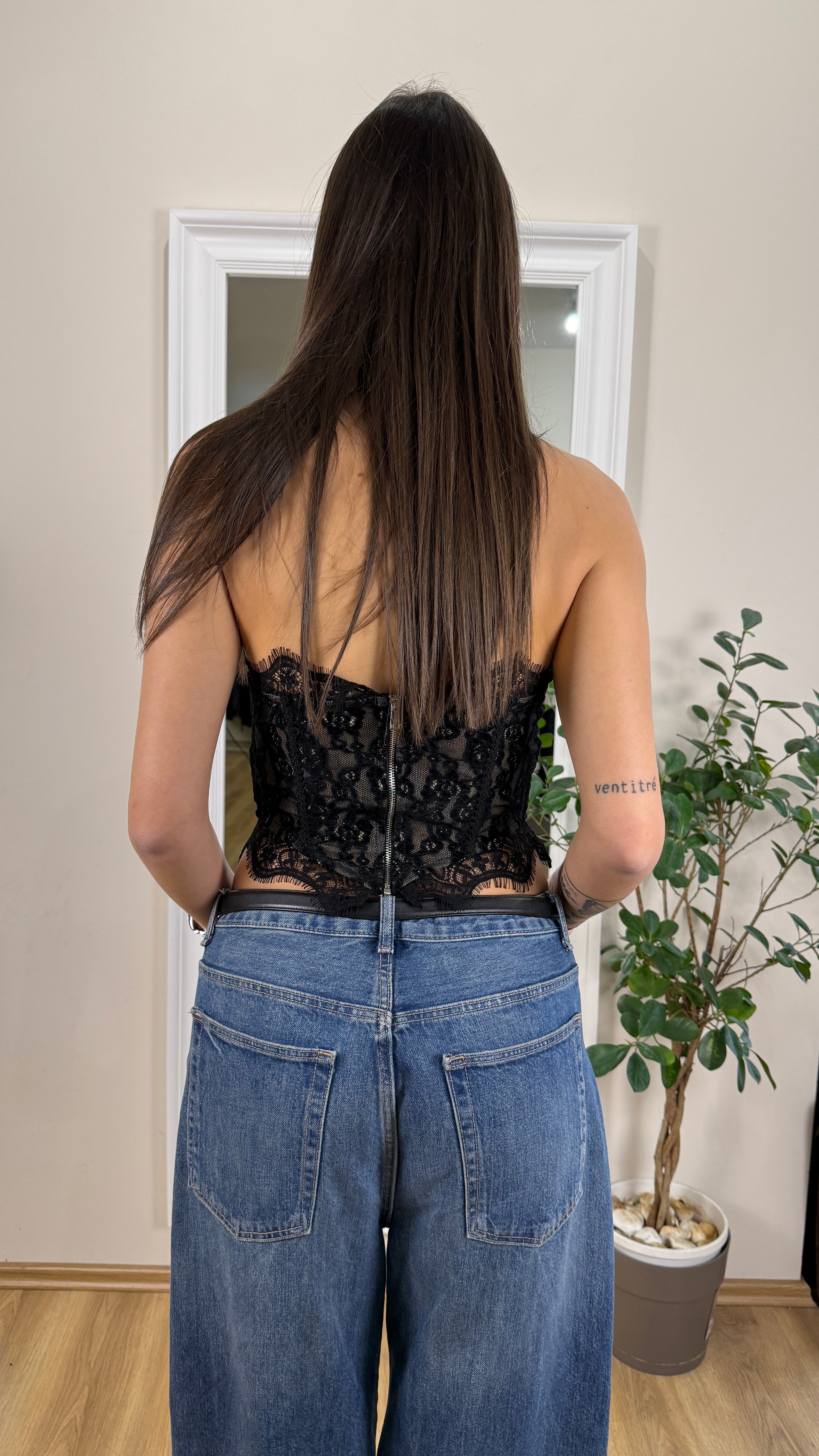 Corpetto in pizzo nero con cerniera posteriore.